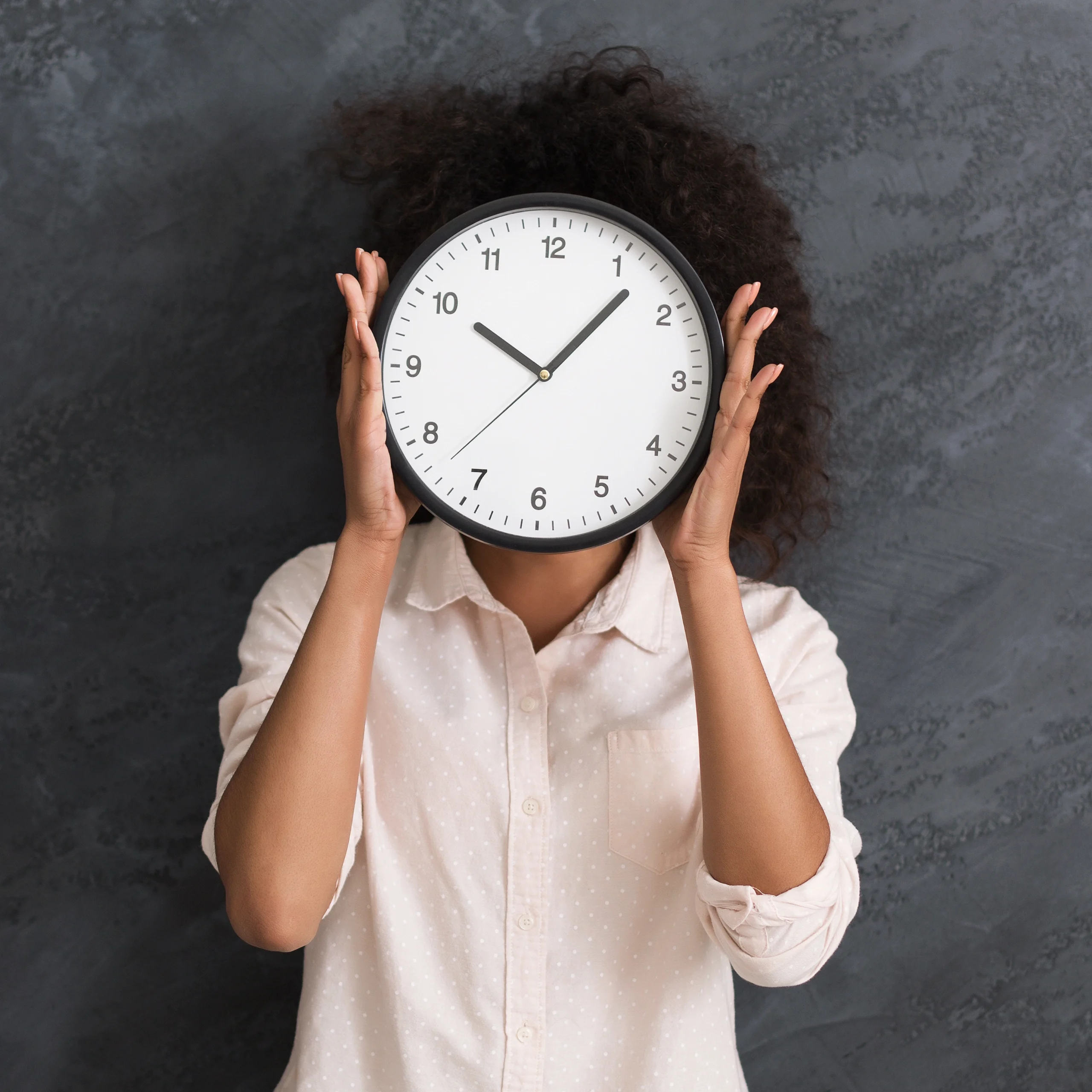Person hiding face behind a large clock Person hiding face behind a large clock