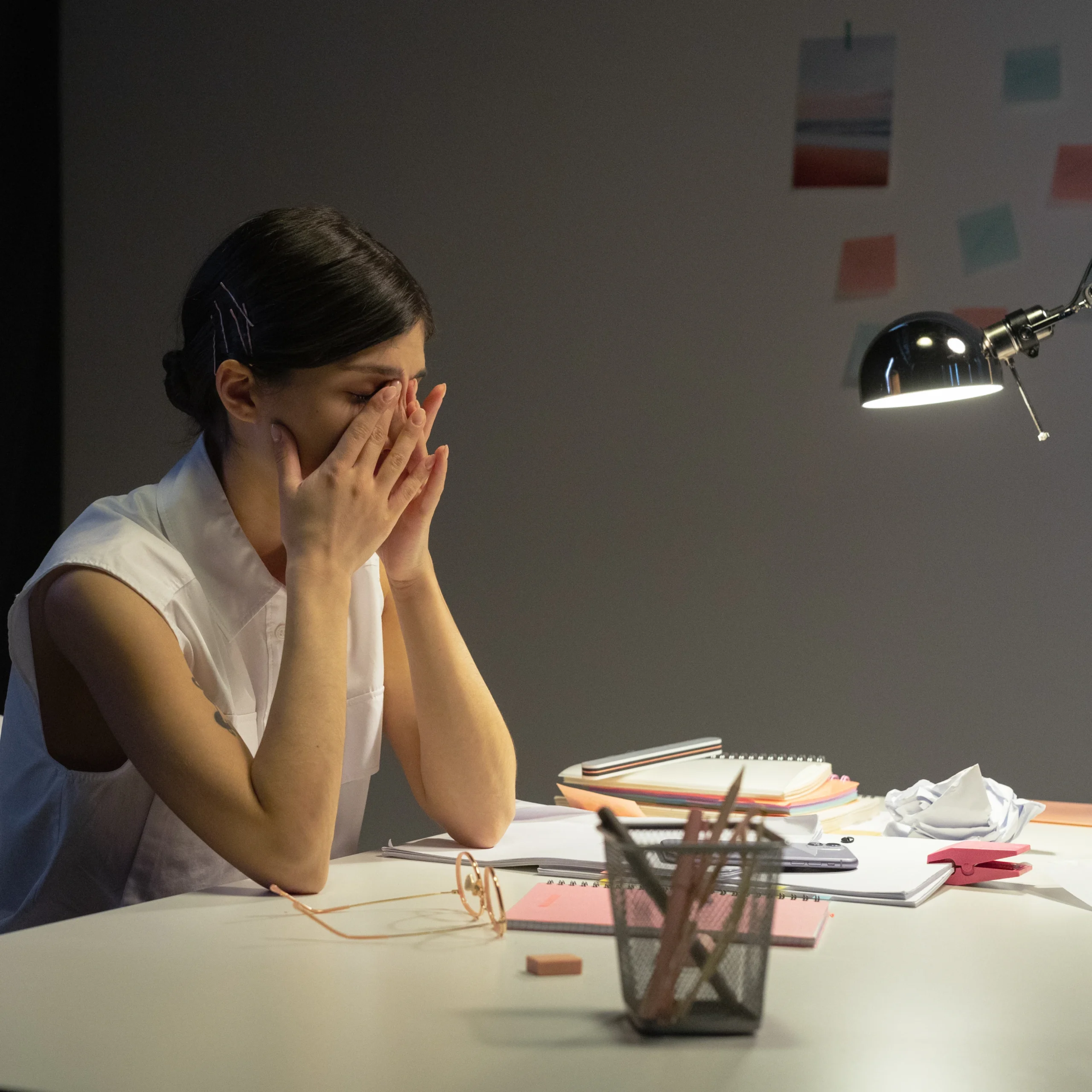 Stressed or tired person rubbing eyes at a desk Stressed or tired person rubbing eyes at a desk