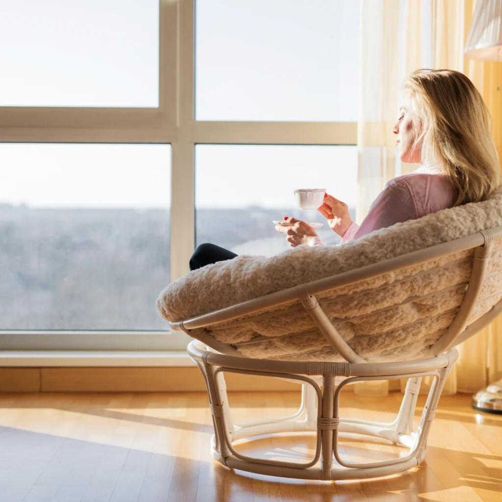Woman with tea by window looking contemplative